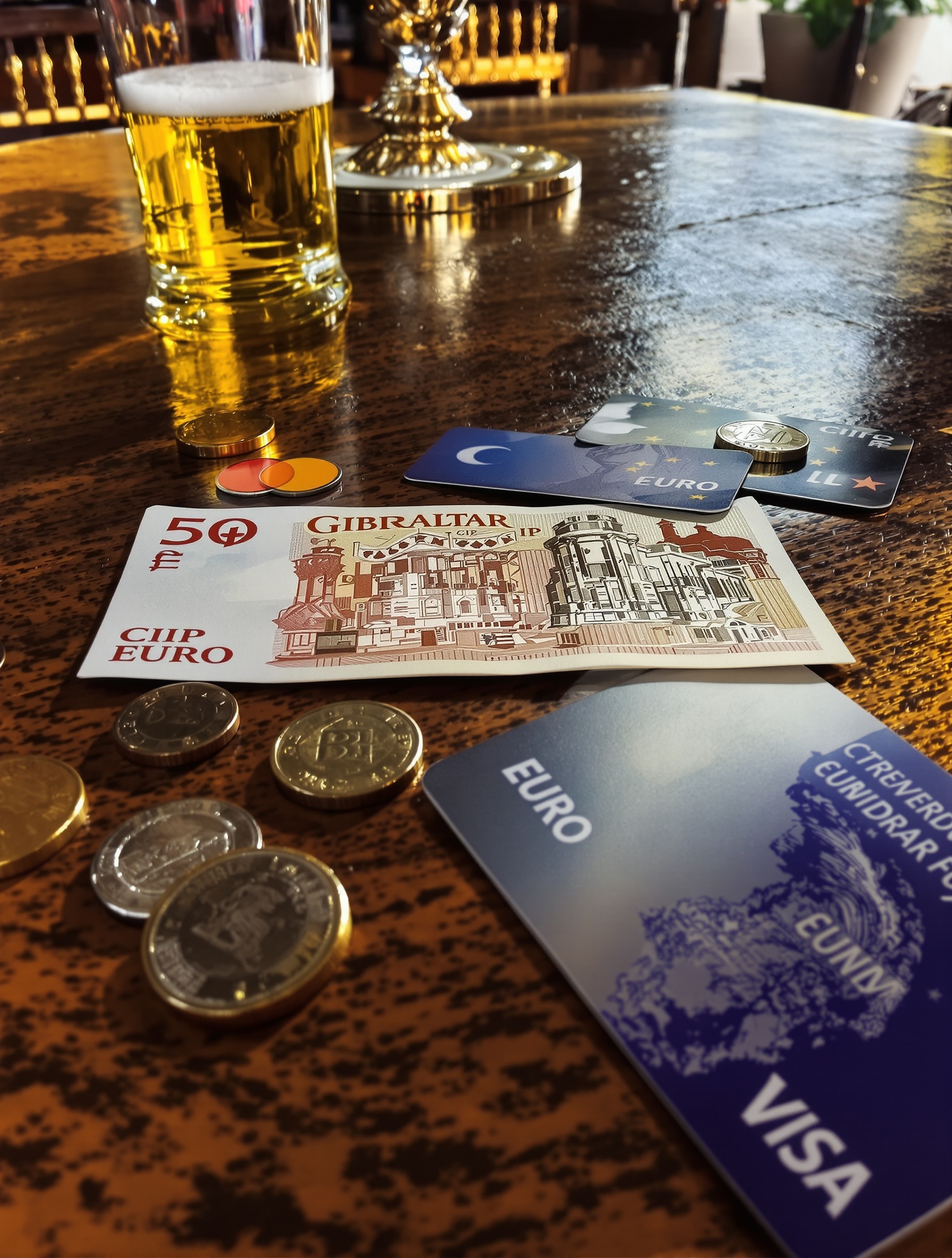 Billet de Livre de Gibraltar posé sur une table aux côtés d'euros et d'une carte bancaire.