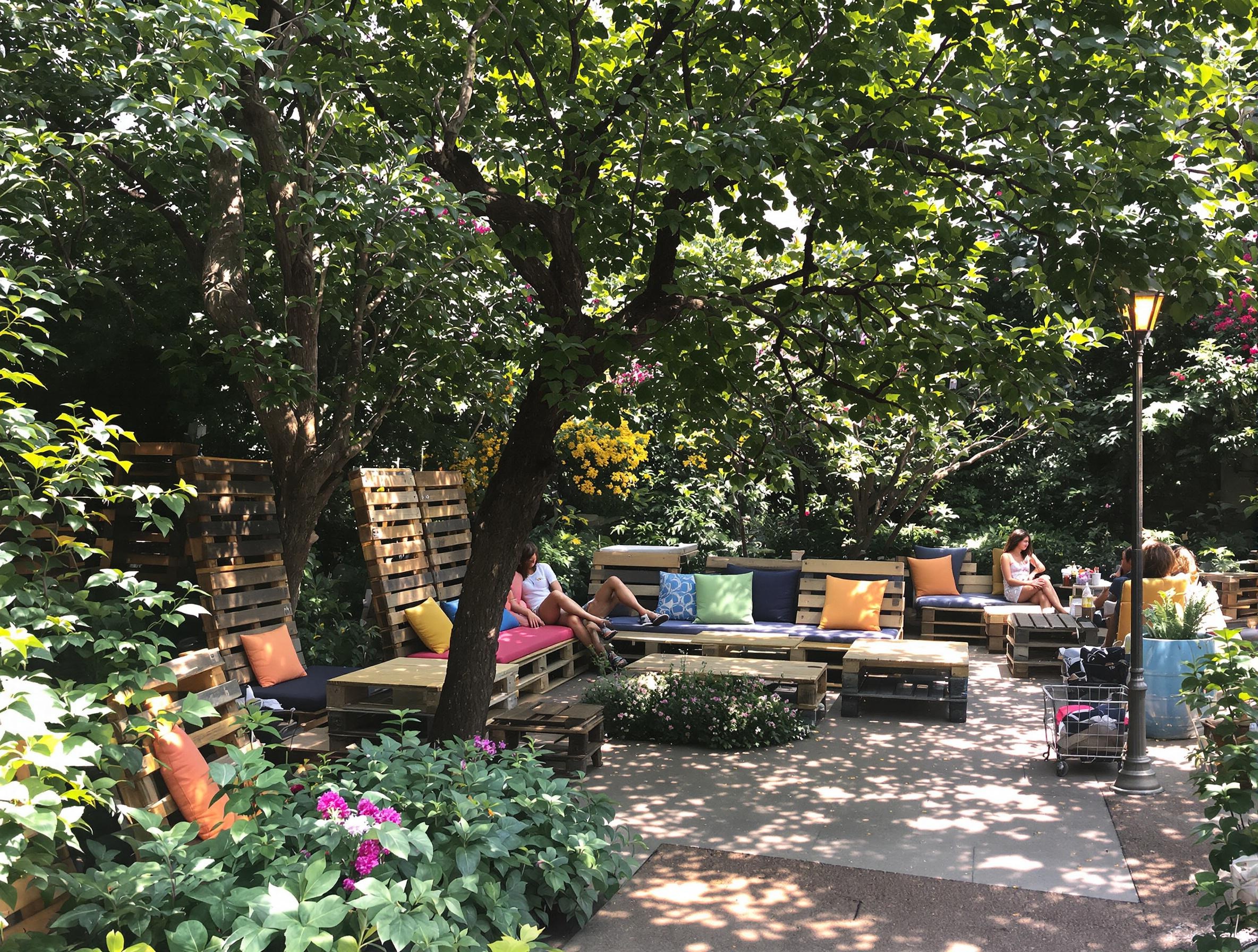 Jardin verdoyant d’Ellátó Kert avec du mobilier en palettes recyclées