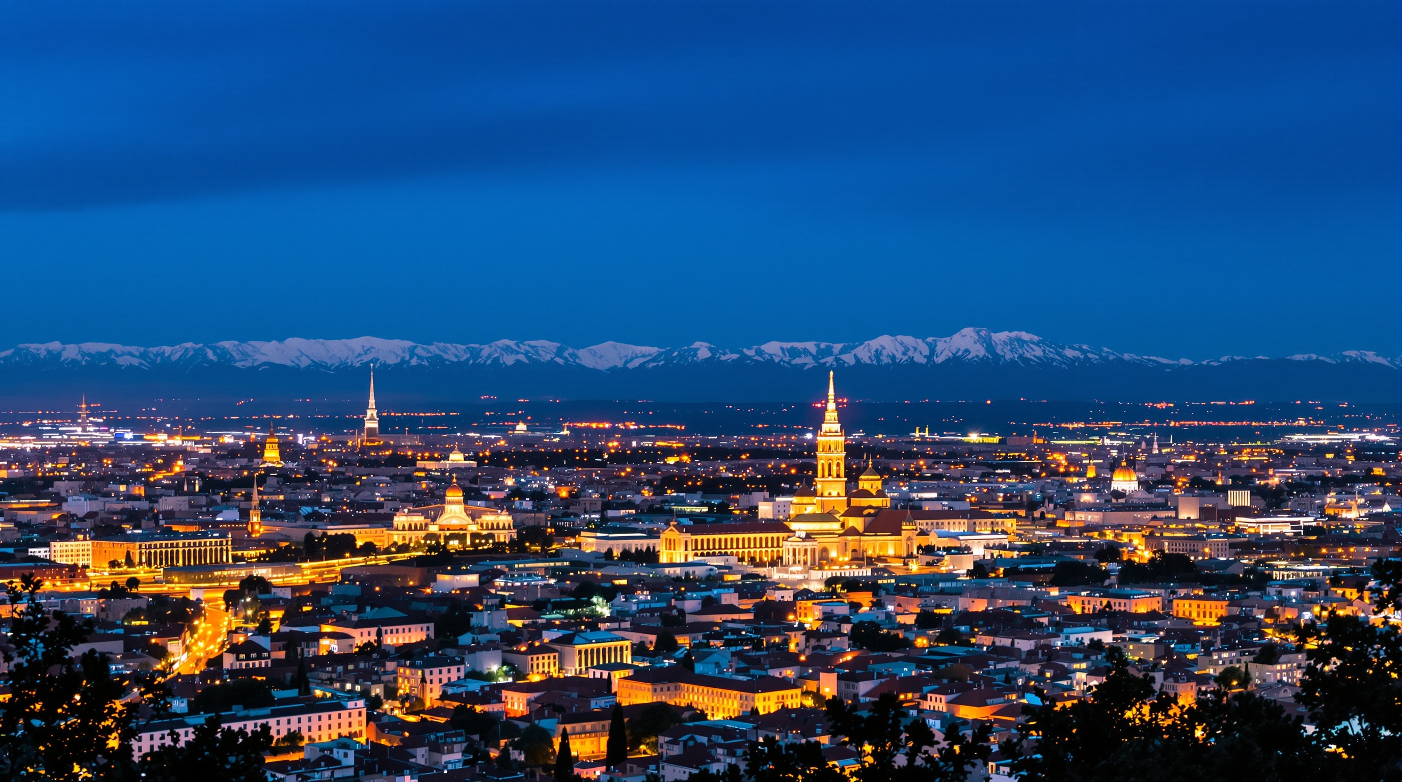 Vue panoramique sur Turin illuminée au crépuscule depuis le Monte dei Cappuccini avec le Mole Antonelliana et les Alpes en arrière-plan.