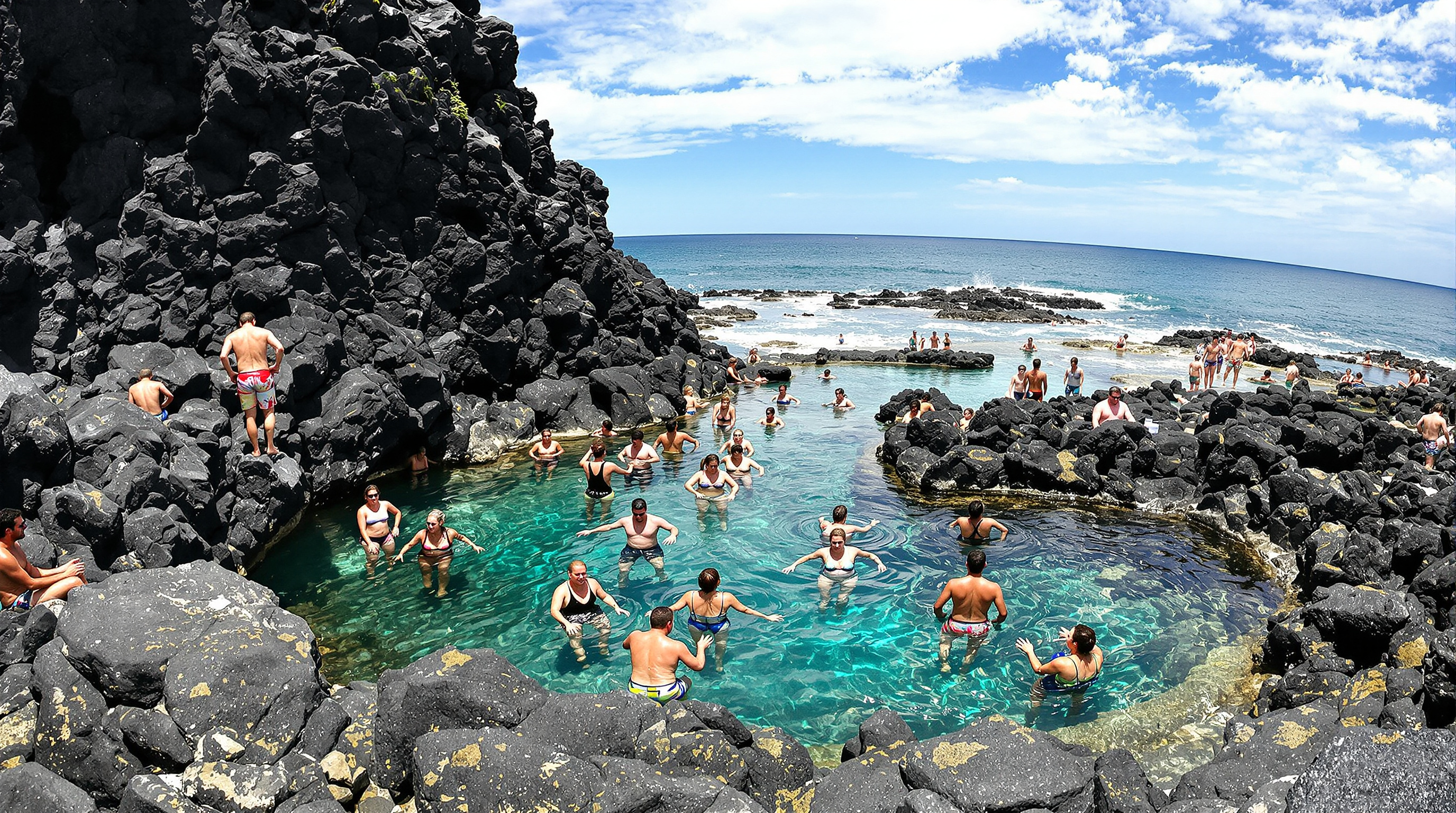 Piscines naturelles de Silveira avec baigneurs locaux, roche volcanique noire et océan en arrière-plan