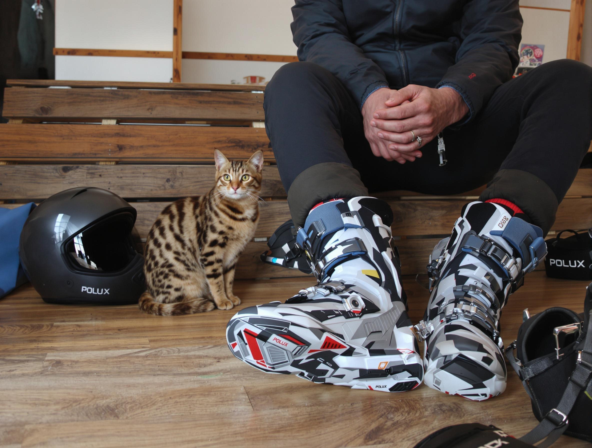 Senior ajuste ses chaussures de ski, casque et protège-dos posés à côté.